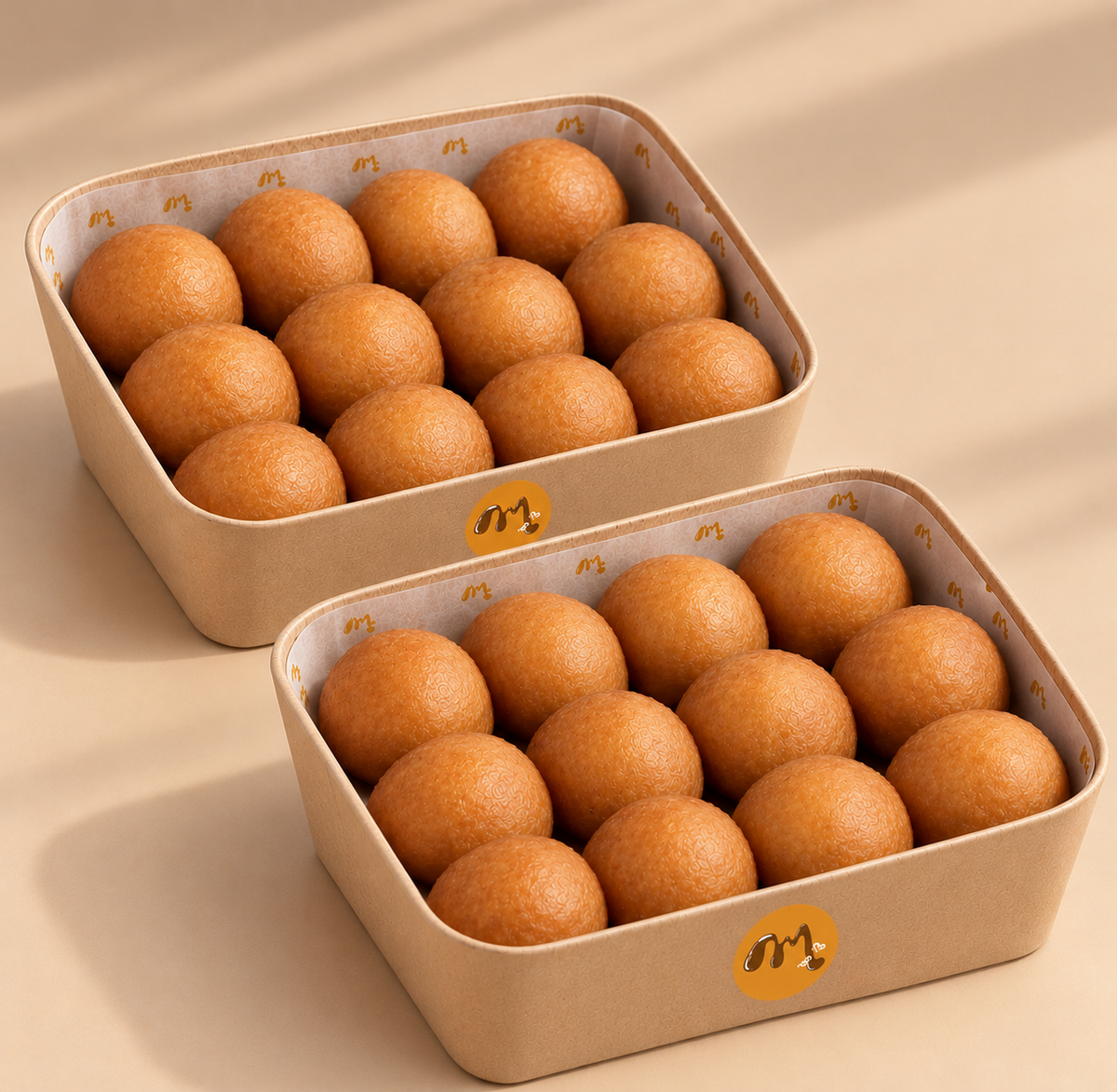 Twenty-four golden Congolese mikate arranged in two kraft boxes with orange Momsukali logos.